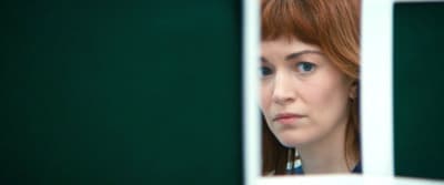 a woman with red hair looking out of a window