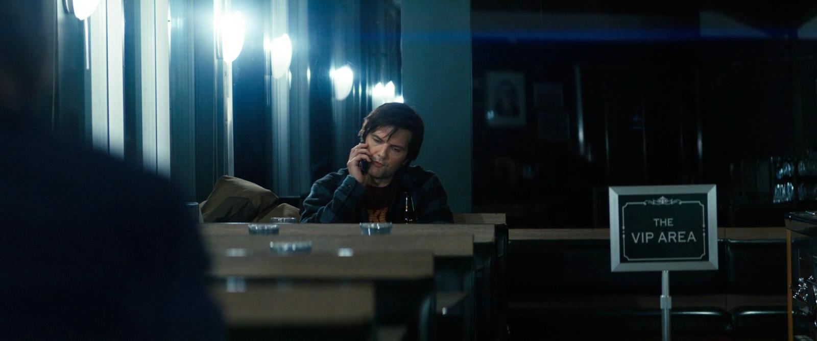 a man sitting at a table talking on a cell phone