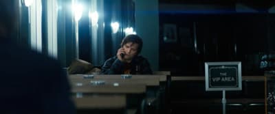 a man sitting at a table talking on a cell phone