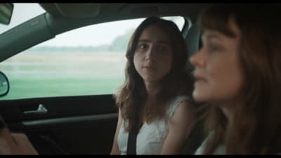 a woman sitting in a car with another woman behind her