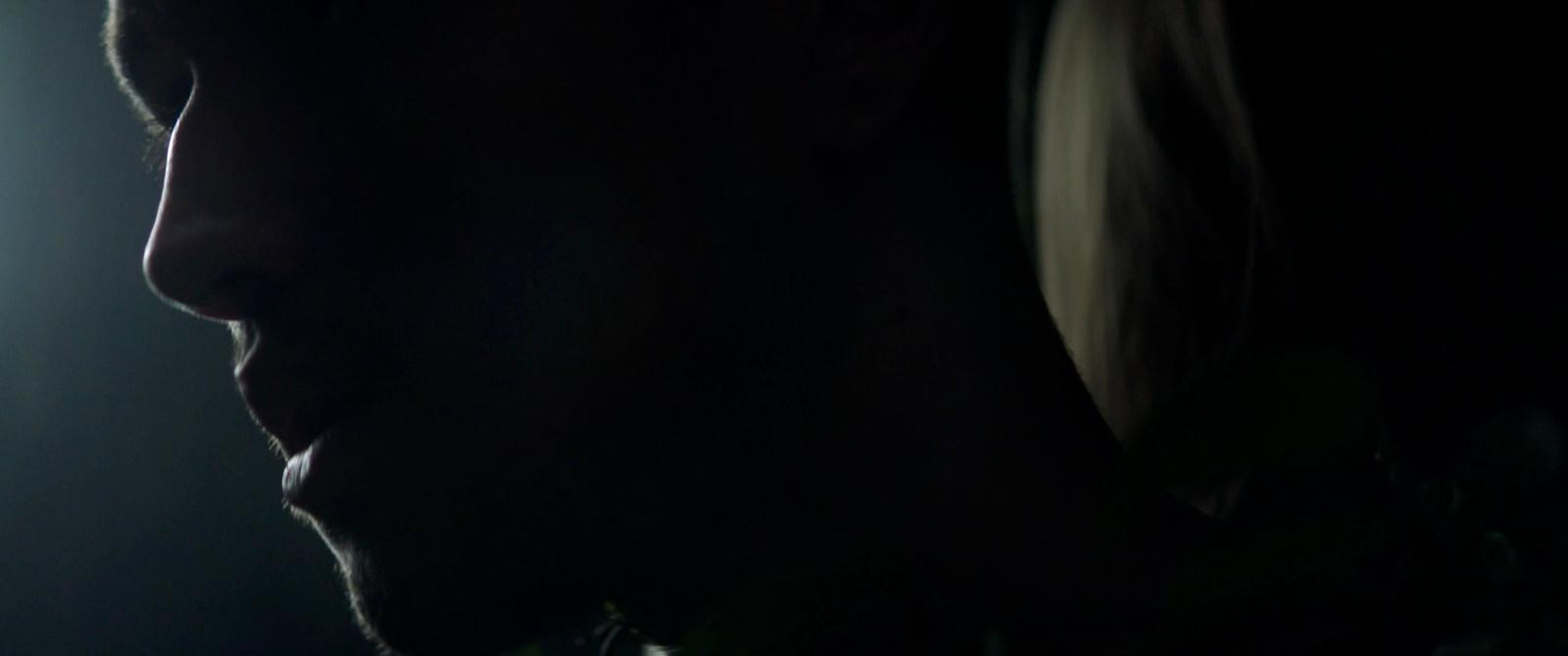 a man with long hair standing in a dark room