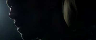 a man with long hair standing in a dark room