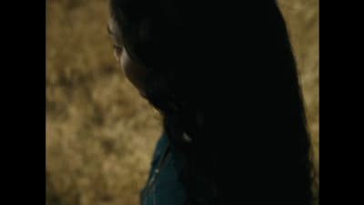 a woman with long hair standing in a field