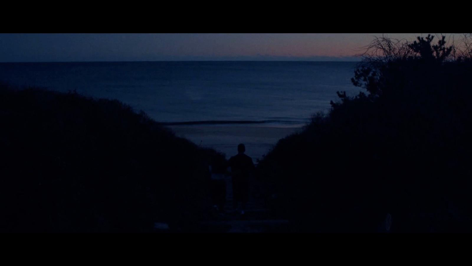 a couple of people standing on top of a hill near the ocean
