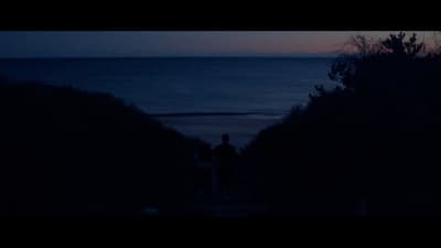 a couple of people standing on top of a hill near the ocean