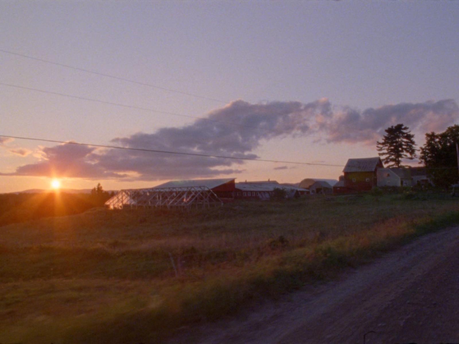 the sun is setting over a farm in the country