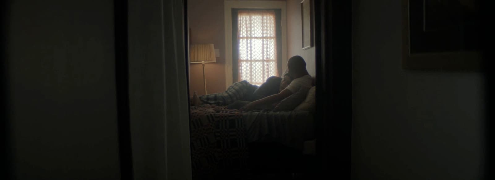 two people sitting on a bed in a dark room