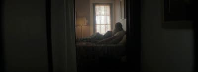 two people sitting on a bed in a dark room