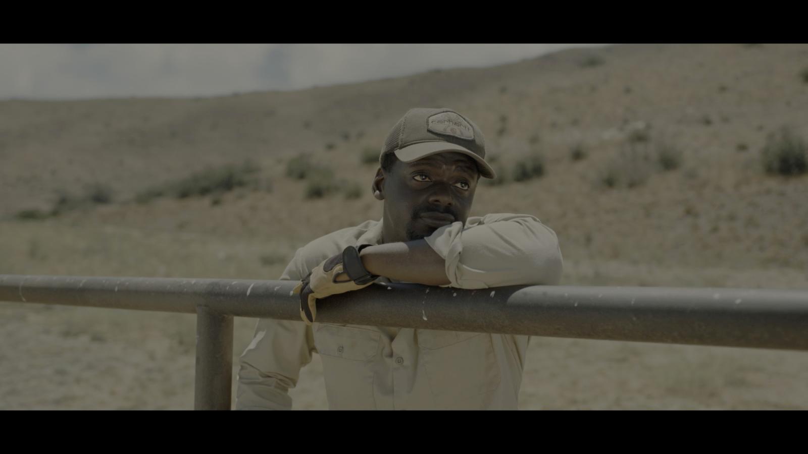 a man leaning on a rail in the desert