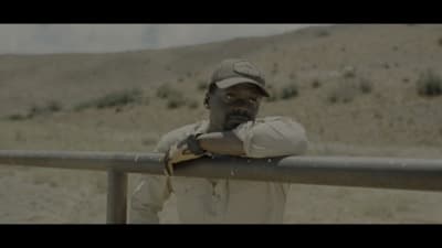 a man leaning on a rail in the desert