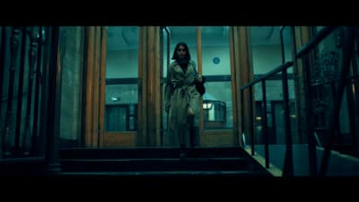 a woman in a trench coat walking down a set of stairs