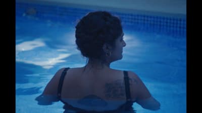 a woman sitting in a pool with a tattoo on her back