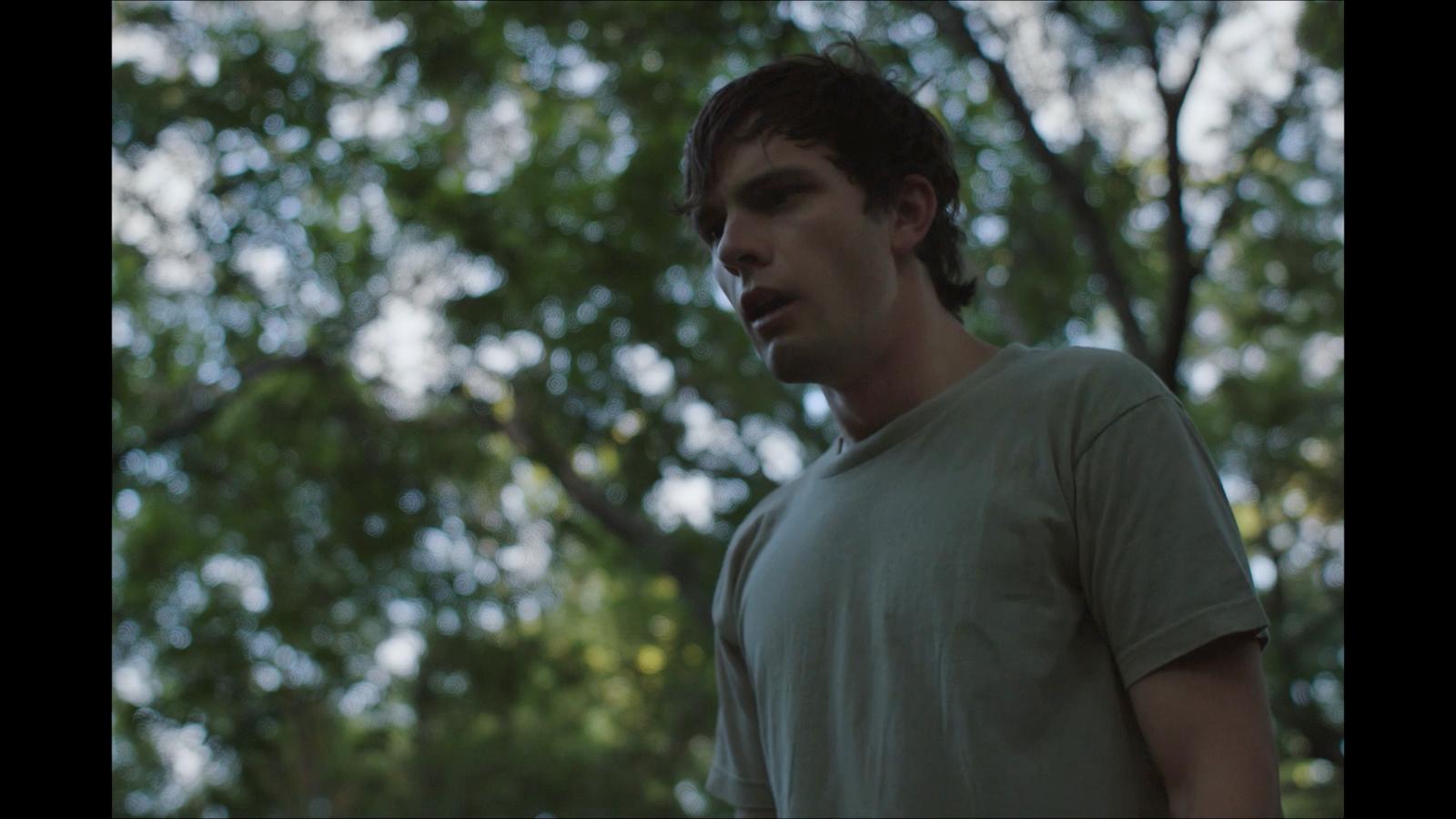 a young man standing in front of a tree