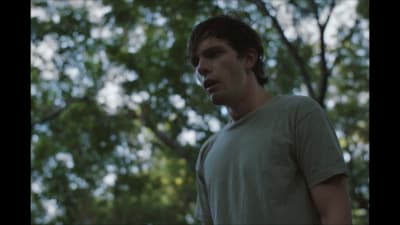 a young man standing in front of a tree