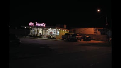 a gas station at night with a neon sign