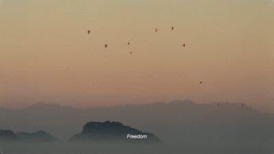 a group of kites flying over a mountain range