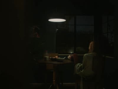 a woman sitting at a table in a dark room