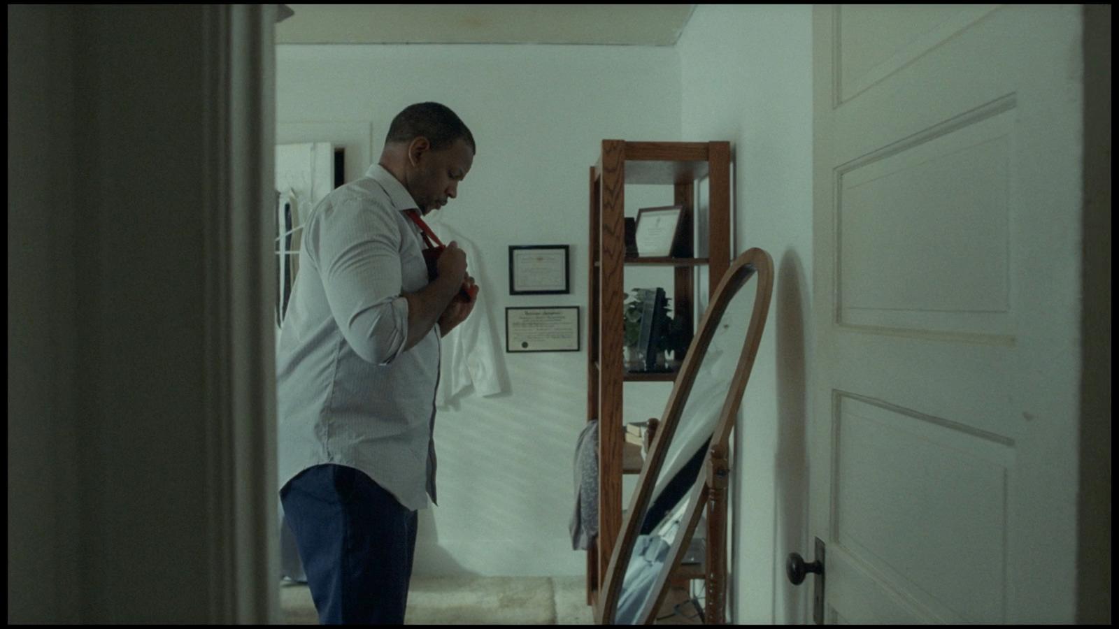 a man in a white shirt is standing in a hallway