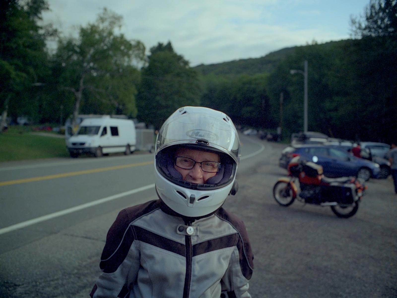 a man wearing a helmet standing next to a motorcycle