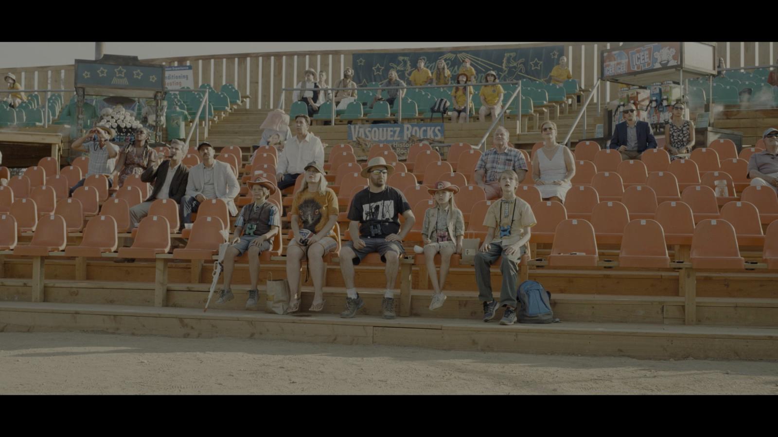 a group of people sitting on top of a bleachers
