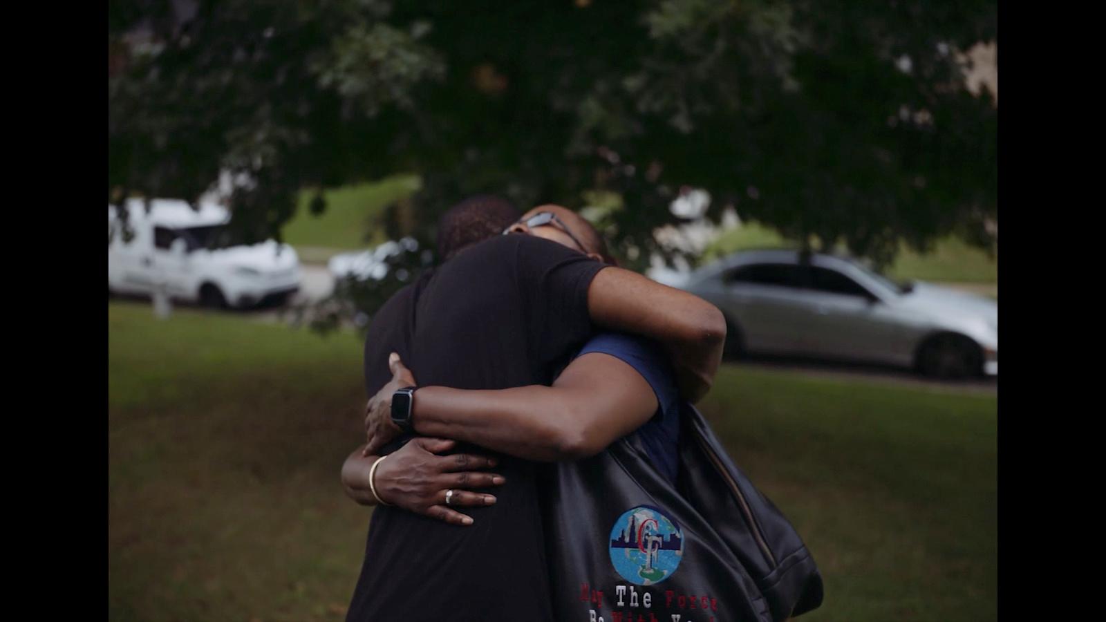 two people hugging each other in a park