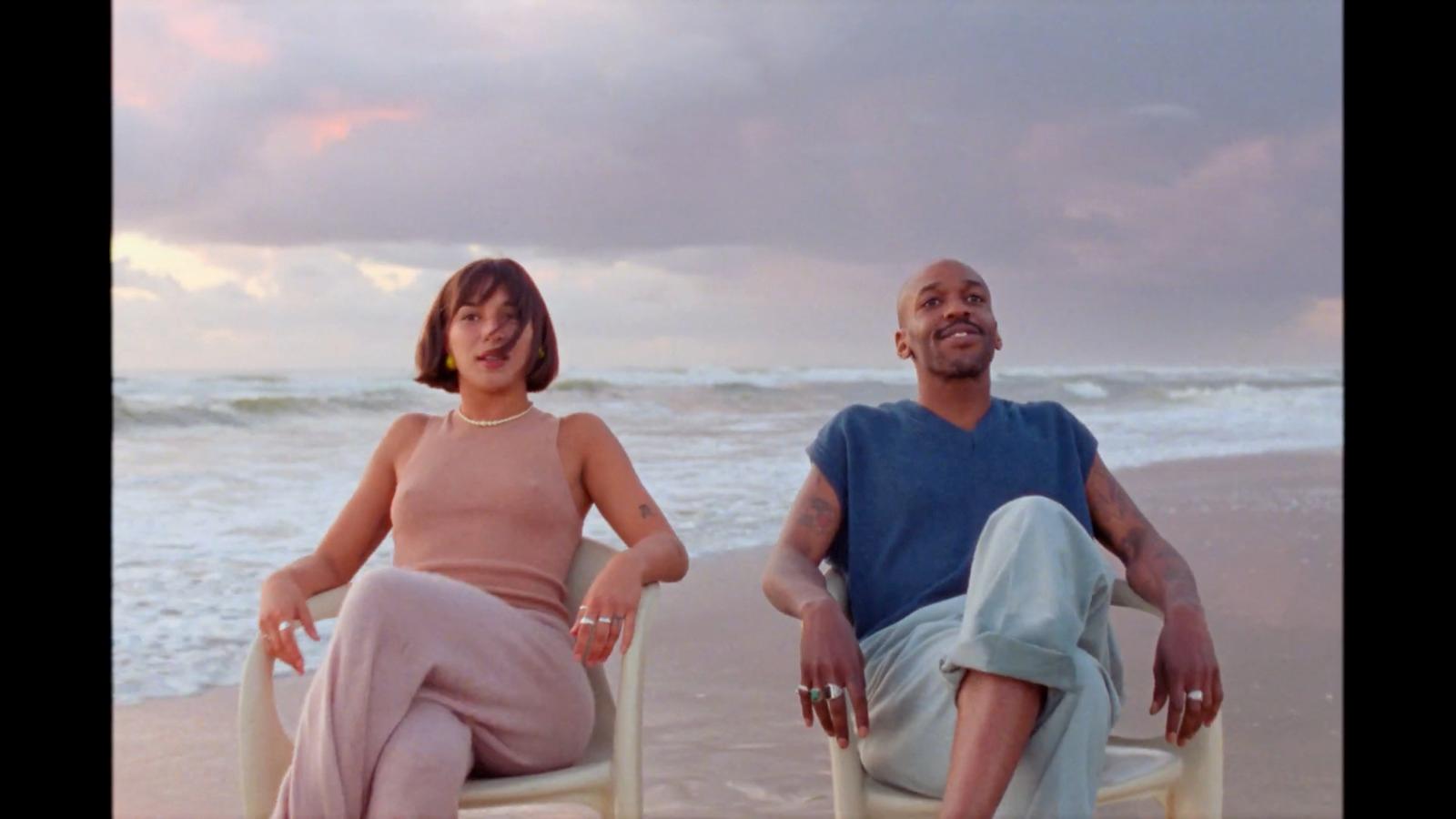 a man and a woman sitting in chairs on the beach