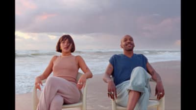 a man and a woman sitting in chairs on the beach