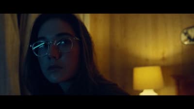 a woman wearing glasses in a dimly lit room