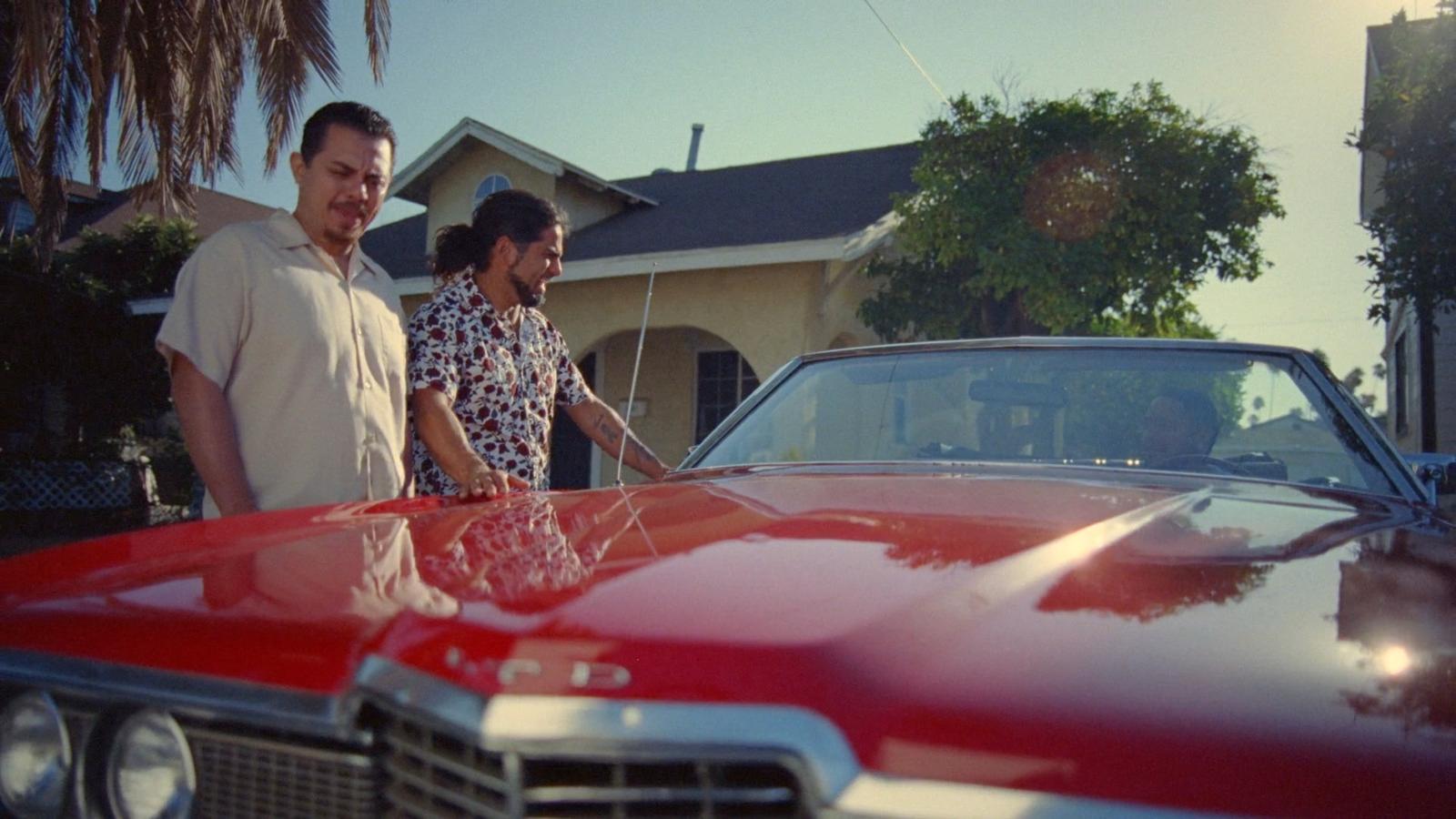 a man and a woman standing next to a red car
