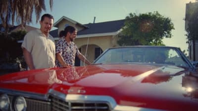 a man and a woman standing next to a red car