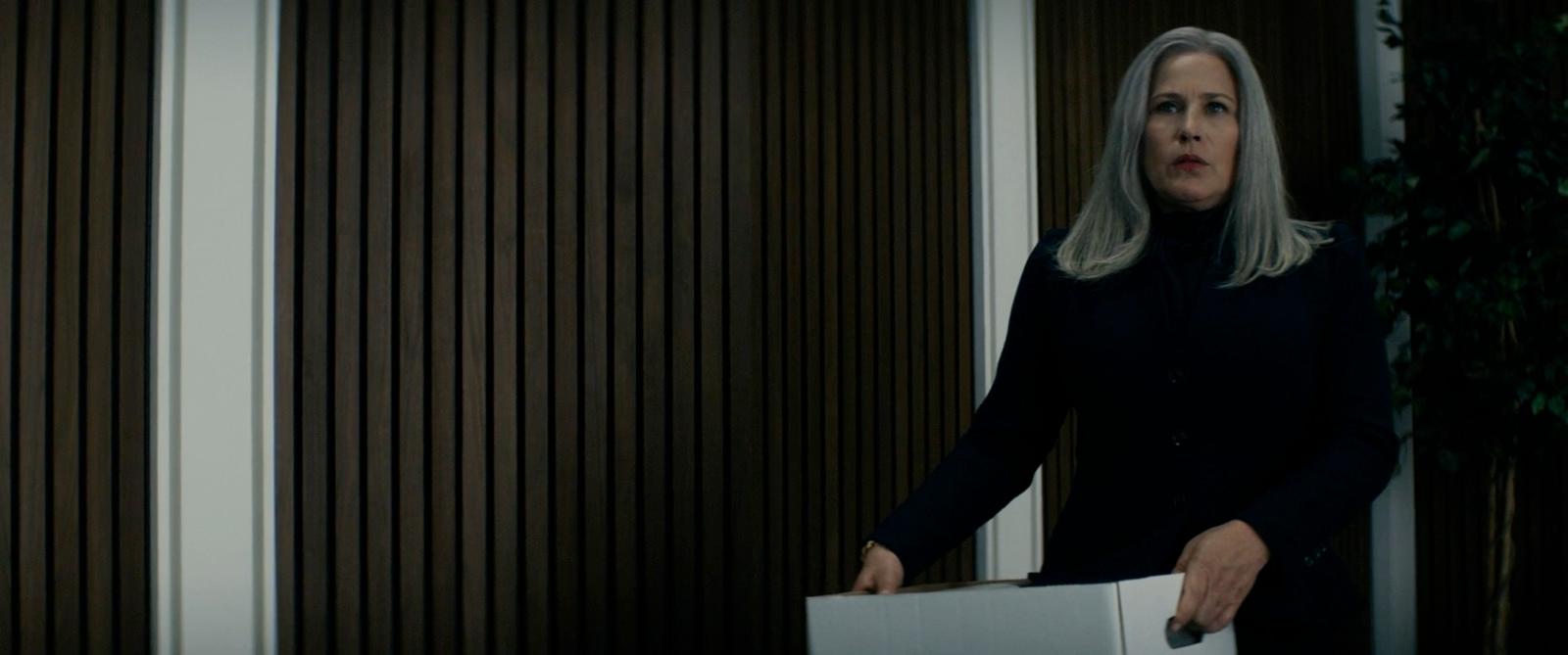 a woman in a black coat holding a box