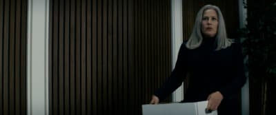a woman in a black coat holding a box