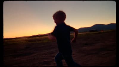 a young boy is playing with a frisbee at sunset