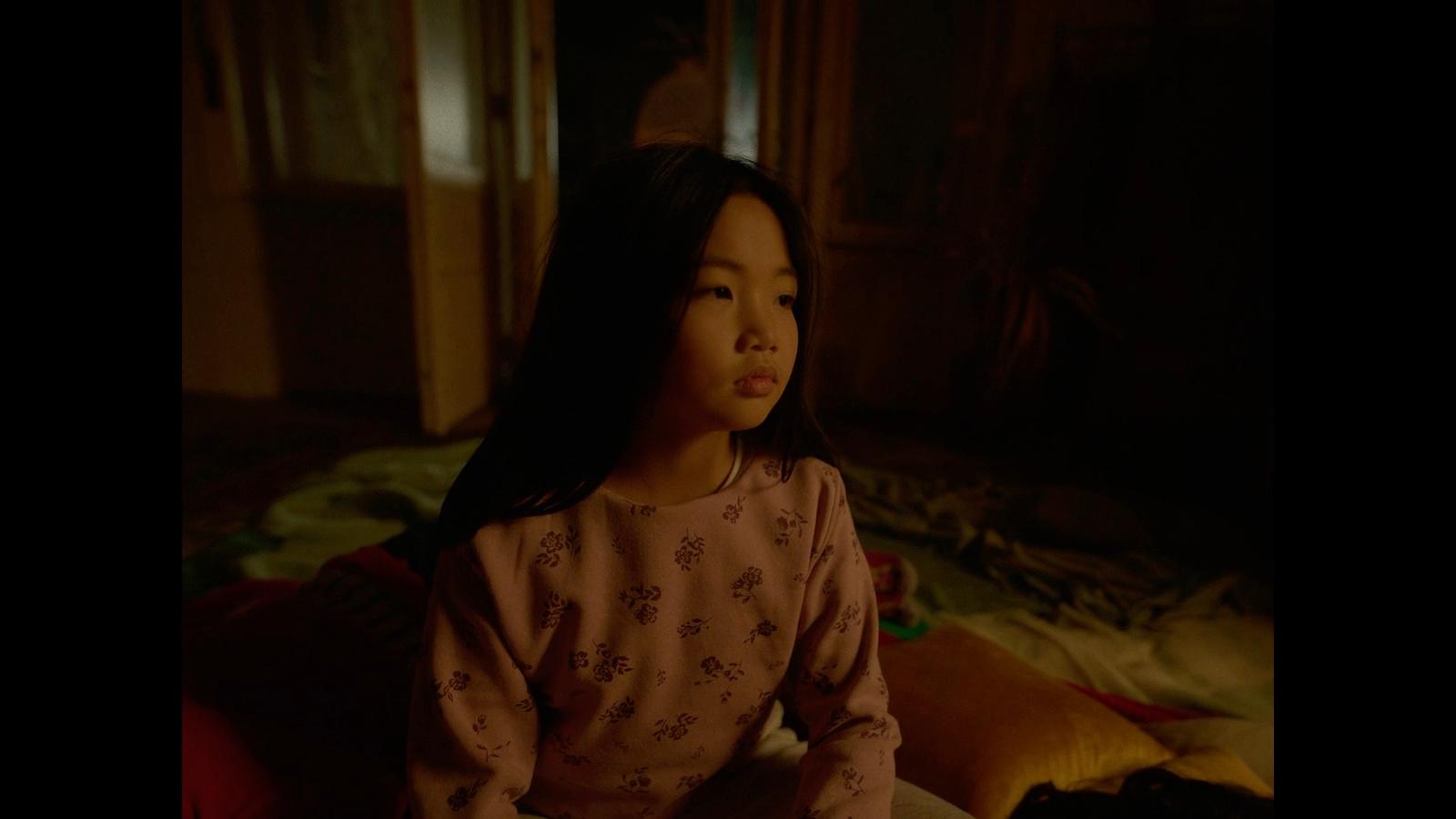 a little girl sitting on a bed in a room