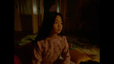 a little girl sitting on a bed in a room