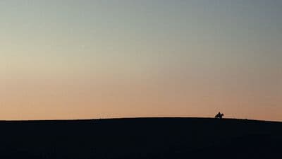 a person sitting on top of a hill at sunset