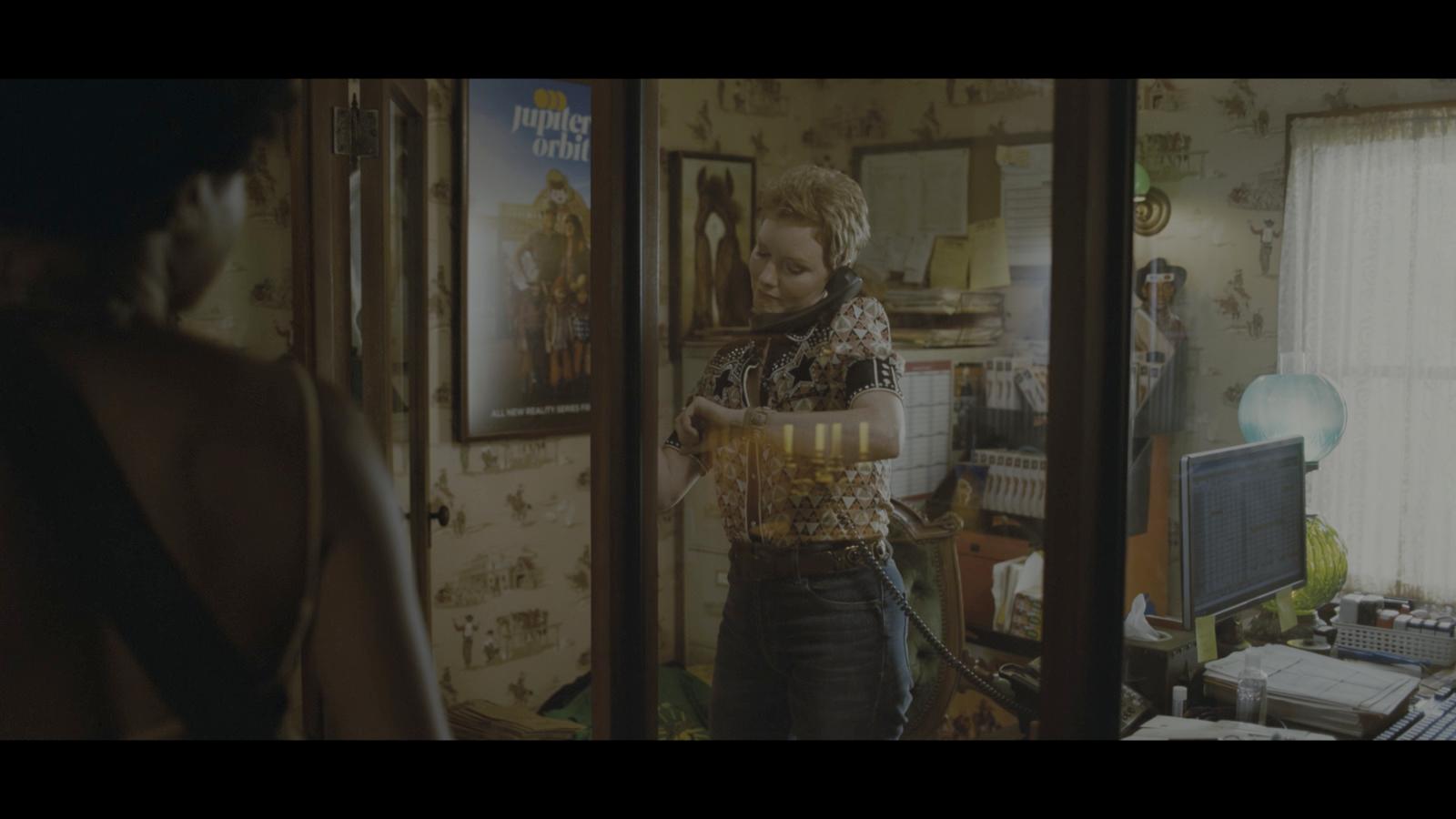 a woman standing in front of a mirror holding a glass