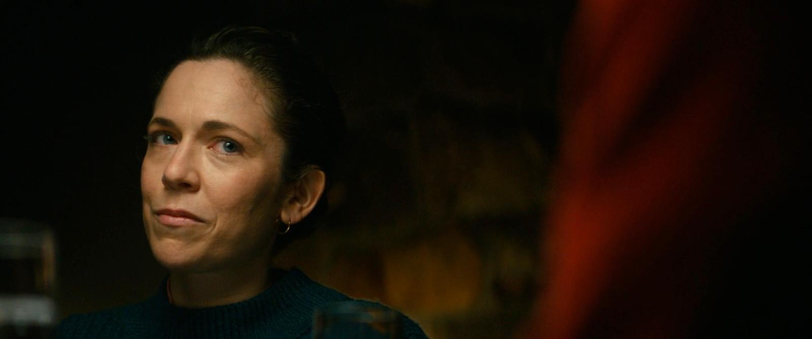 a woman in a dark room with a glass of wine