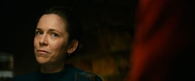 a woman in a dark room with a glass of wine