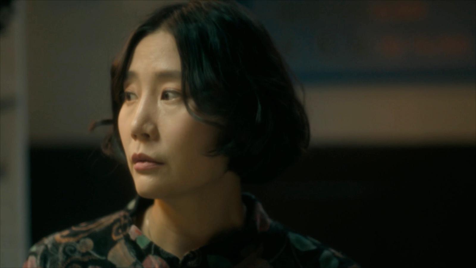 a woman in a floral shirt looking off into the distance