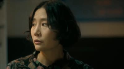 a woman in a floral shirt looking off into the distance