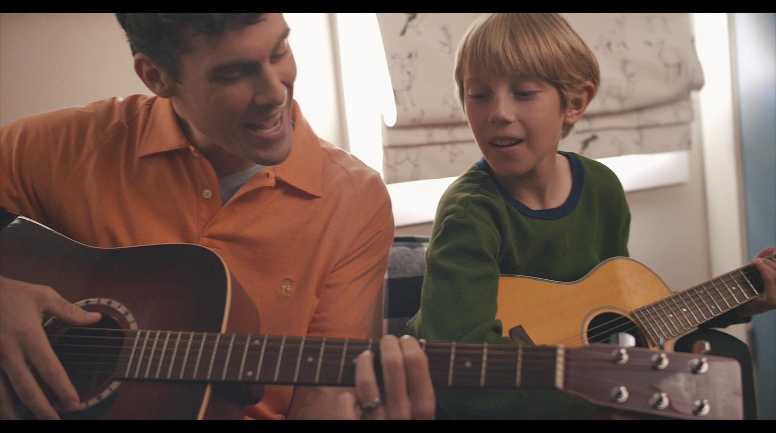 a man playing a guitar with a young boy