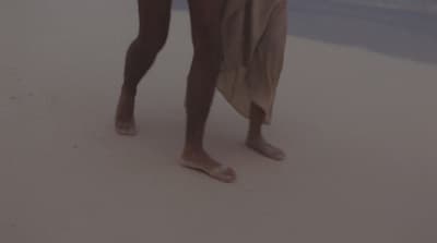 a man standing on a beach holding a surfboard