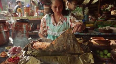a woman preparing food on a table in a kitchen