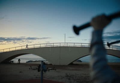 a person holding a baseball bat in front of a bridge