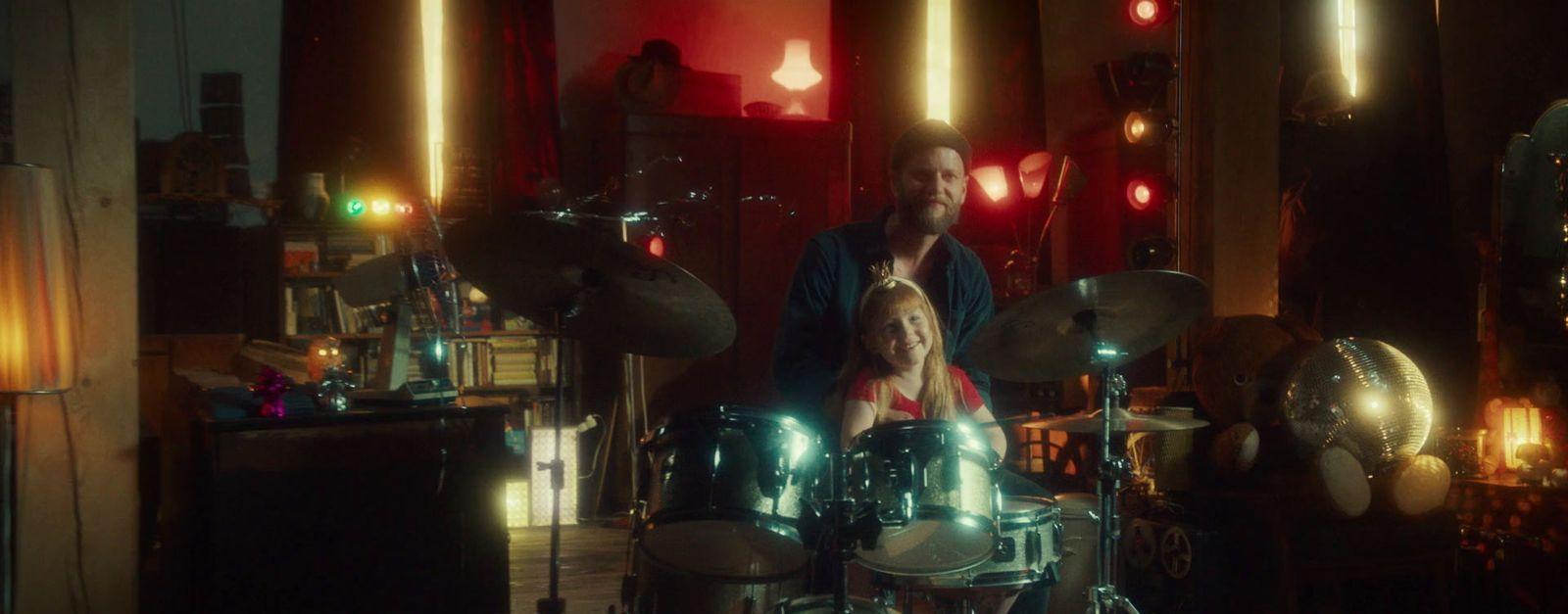 a man and a little girl sitting in front of a drum set
