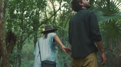 a man and a woman walking through a forest