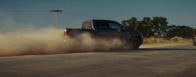 a truck driving down a road with dust behind it