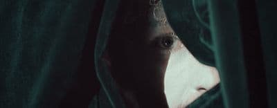 a man peeking out from behind a green curtain