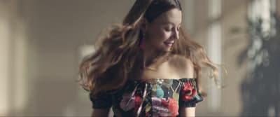 a woman with long hair walking down a hallway